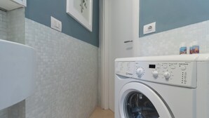 Ein moderner Waschraum mit einer Waschmaschine mit Frontlader, einer gefliesten Wand und einer Tür zu einem anderen Raum.