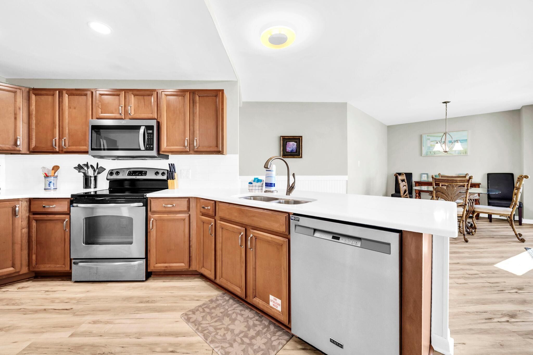 A modern kitchen with wooden cabinets, stainless steel appliances, and a white countertop.