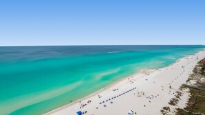 Une plage aux eaux turquoise et limpides, au sable blanc, et une jetée qui s’avance dans la mer.