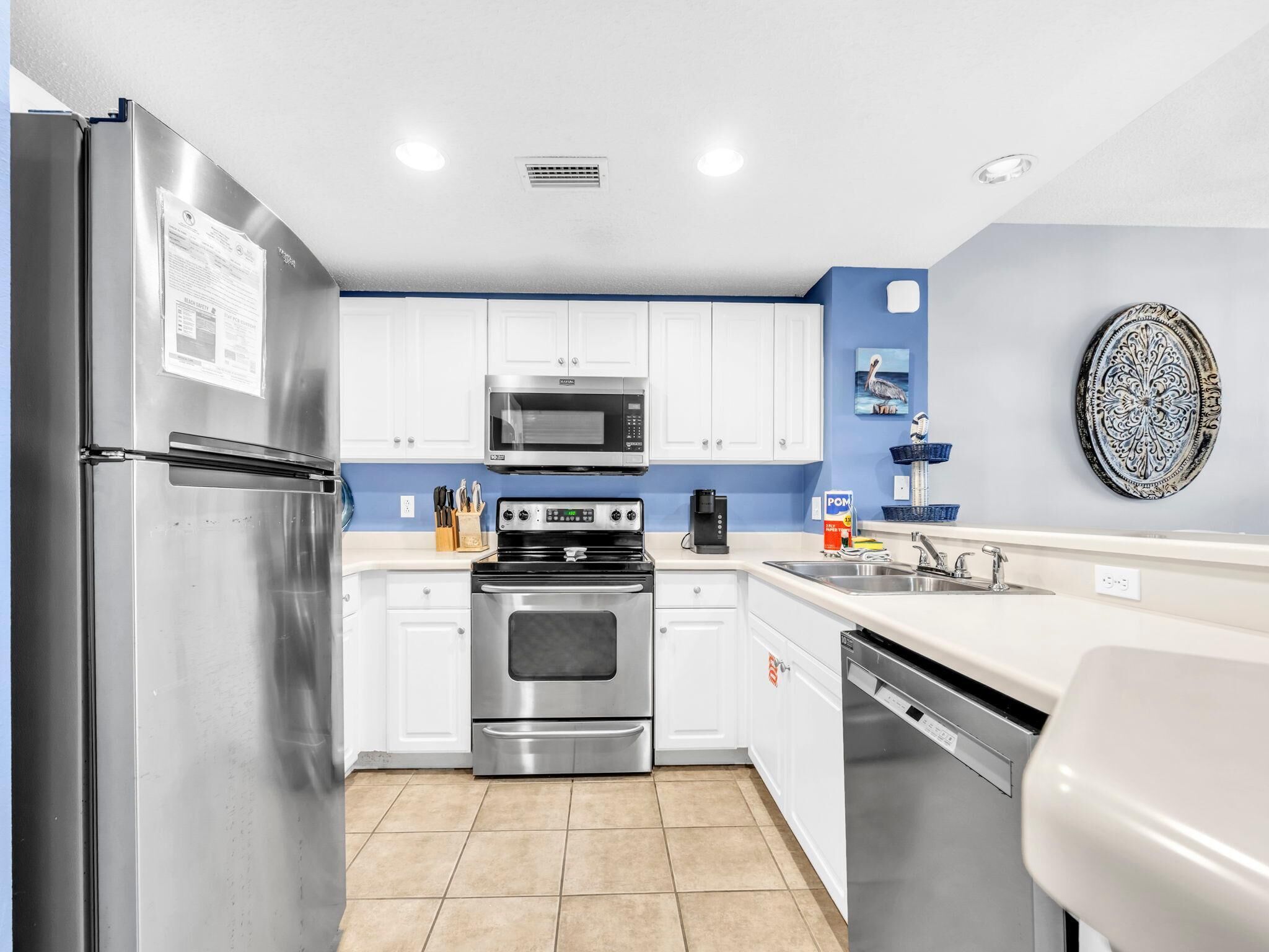 A modern kitchen with stainless steel appliances, white cabinets, and a blue accent wall.