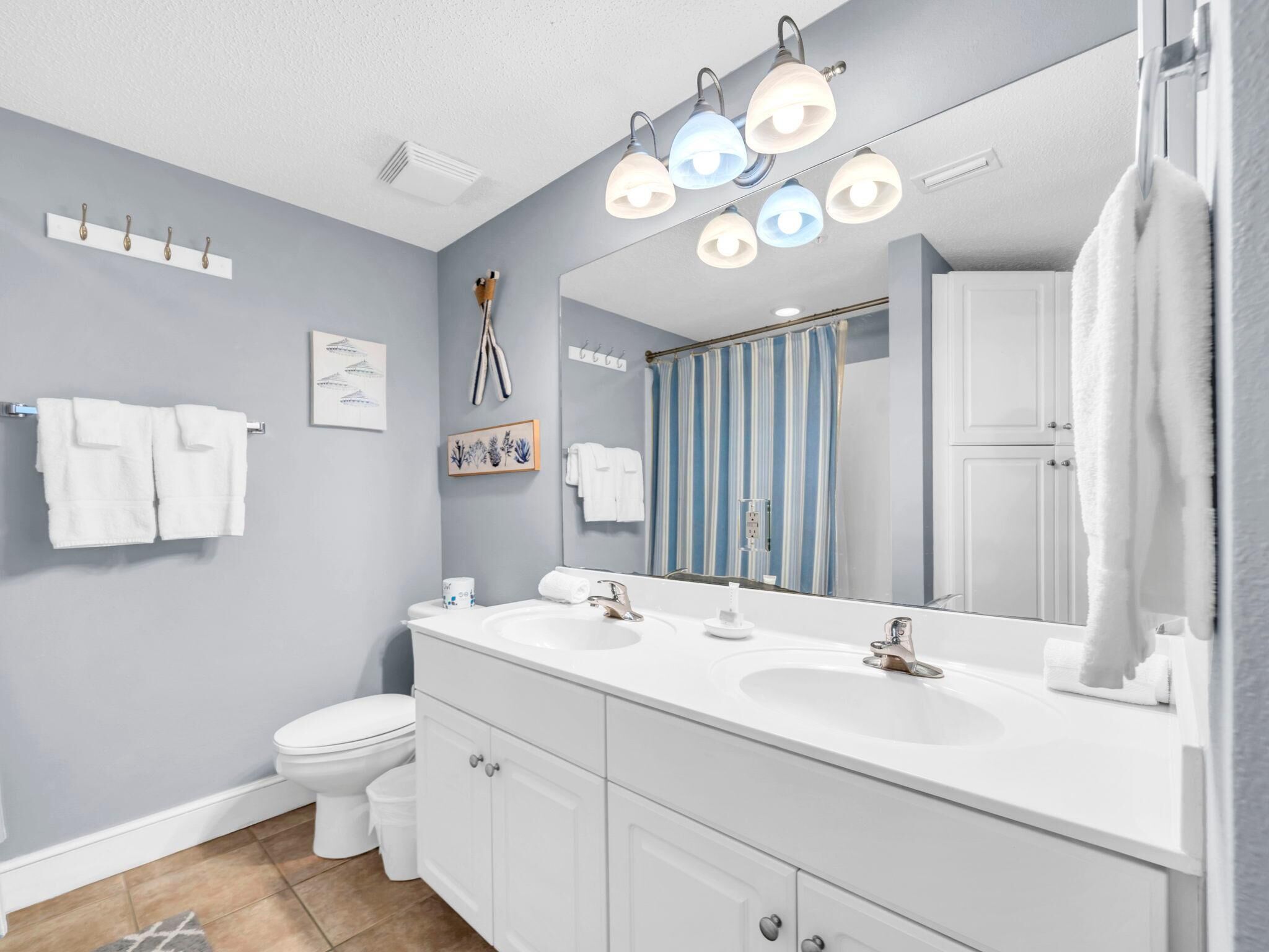Une salle de bain moderne avec un meuble-lavabo à deux vasques, un grand miroir et un rideau de douche.