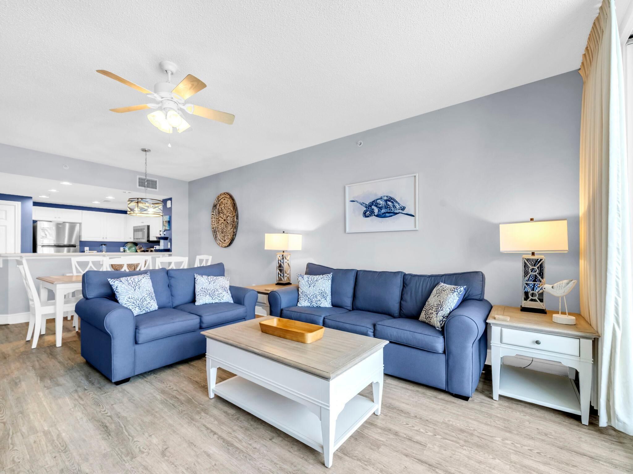 Un salon moderne avec un canapé bleu, une table basse en bois et un ventilateur de plafond.