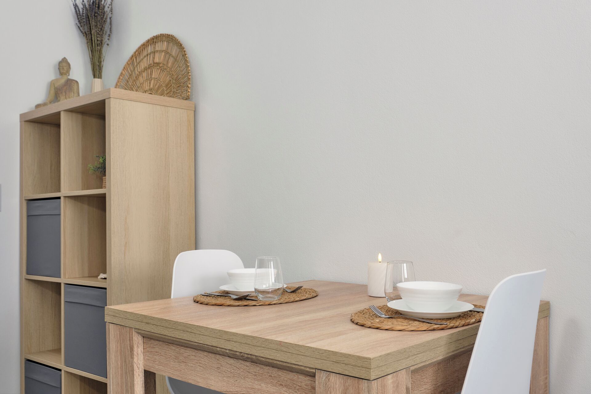 A dining table with a light wood finish, two white chairs, and a wooden sideboard with shelves.