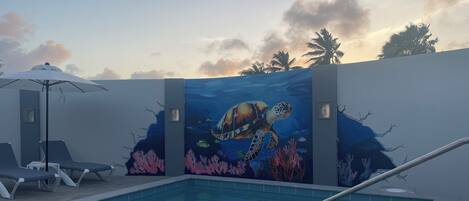 Alberca al aire libre, sombrillas en la alberca y camastros