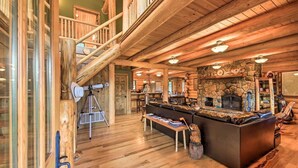 A spacious log cabin interior with a stone fireplace, wooden staircase, and a cozy seating area. - The 'Cool Creek Ranch' w/ 95 Acres on Yaak River (Troy)