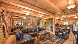 A log cabin interior with a leather sofa, a coffee table, and a dining area. - The 'Cool Creek Ranch' w/ 95 Acres on Yaak River (Troy)