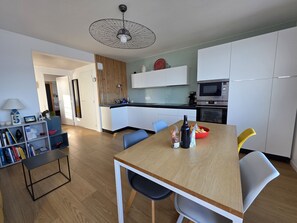 Una cocina moderna con armarios blancos, una mesa de comedor de madera y un microondas integrado.