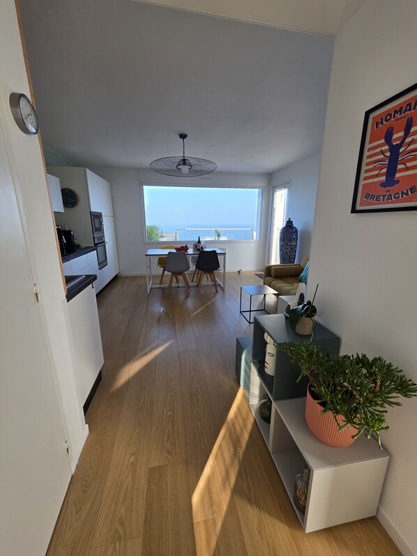 Een modern appartement met keuken, eethoek en een groot raam met uitzicht op zee.