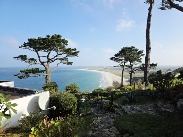 A coastal landscape with a view of the sea and beach, surrounded by trees and a stone pathway. - BEAUTIFUL, QUIET COCOON WITH STUNNING SEA VIEW (Plouguerneau)