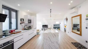 A modern kitchen with white cabinetry, a central island, and a dining area with a large mirror. - Monaco Border - 100% new with see view (Beausoleil)