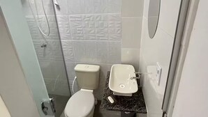 Ein kleines Badezimmer mit Toilette, Waschbecken und Dusche.