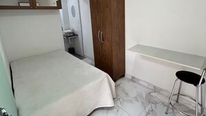 Ein Schlafzimmer mit Bett, Holzschrank, Schreibtisch und Badewanne.