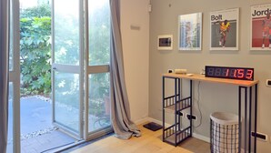 A modern room with a sliding glass door leading to a garden, a digital clock, and sports memorabilia on the wall. - Loft Nicholas in Milano (Milan)