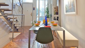 A dining area with a staircase, a dining table with chairs, and a view of the outside through a door. - Loft Nicholas in Milano (Milan)