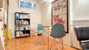 A room with a wooden floor, a bookshelf, a table with chairs, a radiator, and a large abstract painting. - Loft Nicholas in Milano (Milan)