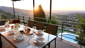 Ein Esstisch mit Geschirr, Gläsern und einer Blumenvase, mit Blick auf eine schöne Aussicht und einen Pool.