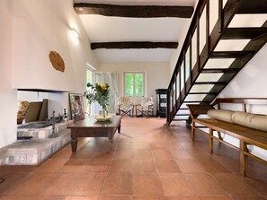 A spacious living room with a fireplace, a wooden staircase, and a view of the outdoors. - Casale Bera Hills View Private Pool and Garden (Cossano Belbo)