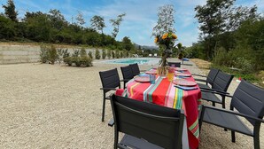 An outdoor dining area with a table set for six, surrounded by chairs, overlooking a swimming pool and a natural landscape. - Casale Bera Hills View Private Pool and Garden (Cossano Belbo)