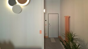 En hall med en dörr, ett element och en krukväxt.