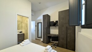 Et moderne hotelværelse med en stor seng, et skrivebord, et fjernsyn og et garderobeskab.