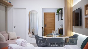 Une chambre d’hôtel moderne comprenant un coin repas, un canapé, une télévision et une porte en bois.
