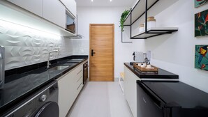 Une cuisine moderne équipée d’un lave-linge, d’une porte en bois et d’une étagère avec des bocaux.