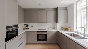 A modern kitchen with built-in appliances, a large window, and a minimalist design. - The Portland - Marylebone - by Frankie (London)