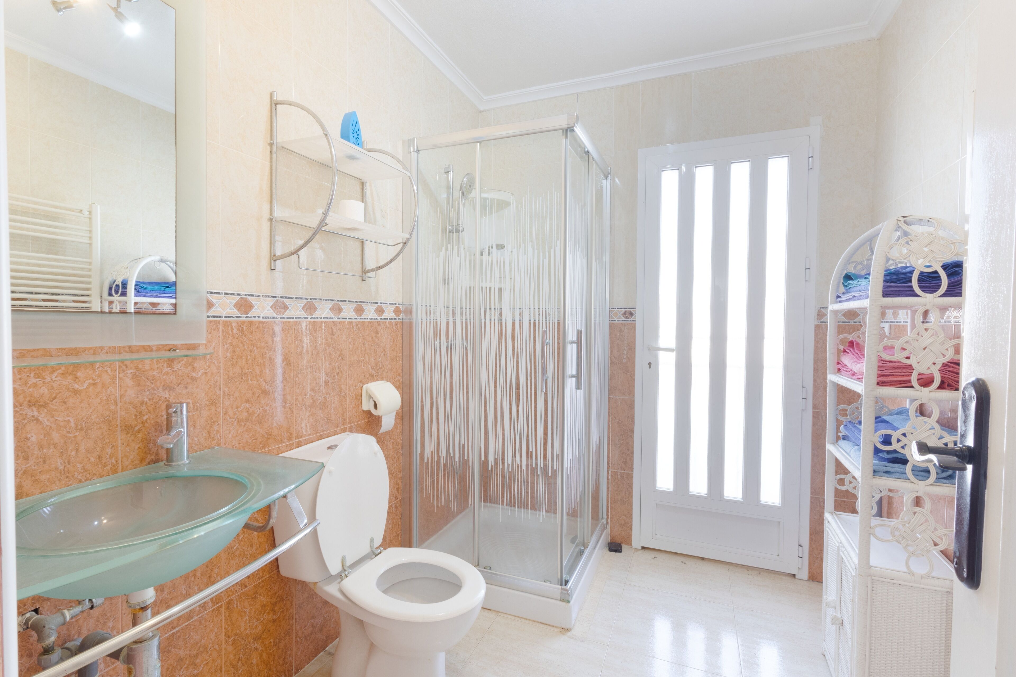 A bathroom with a glass sink, toilet, and a glass-enclosed shower.
