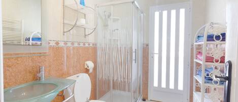 A bathroom with a glass sink, toilet, and a glass-enclosed shower.