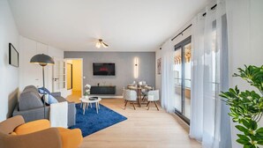 Una sala de estar moderna con un sofá, sillones, una mesa de centro y un televisor montado en la pared.