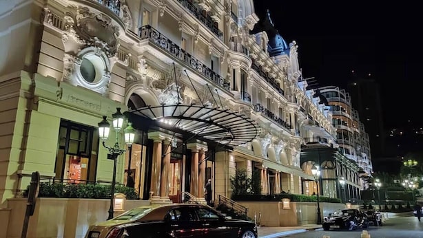 Un hotel imponente de arquitectura ornamentada, con un acceso cubierto y un coche negro estacionado frente a él.