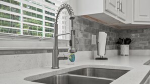 A modern kitchen with a stainless steel sink, a flexible faucet, and a window with blinds. - Perfect Get-Away In The Heart Of Downtown Florence (Florence)