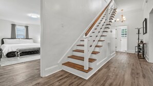 A modern interior with a staircase, a bedroom with a bed and bench, and a hallway with a door leading to another room. - Perfect Get-Away In The Heart Of Downtown Florence (Florence)