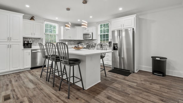 A modern kitchen with white cabinetry, stainless steel appliances, and a central island with bar stools. - Perfect Get-Away In The Heart Of Downtown Florence (Florence)