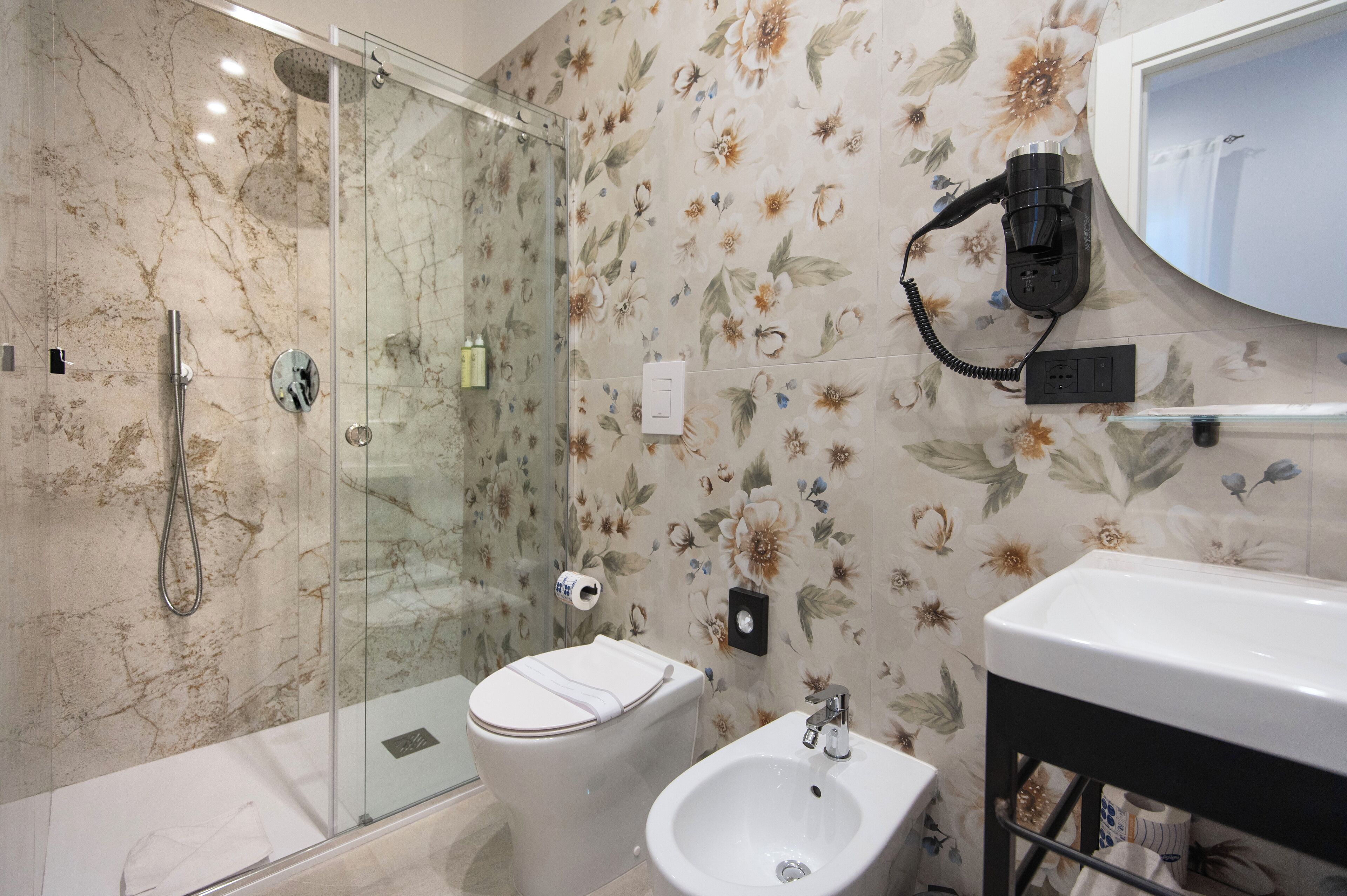 A bathroom with a glass-enclosed shower, a toilet, and a sink.