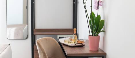 A modern room with a wooden table, a chair, a potted orchid, and a bottle of champagne.