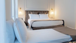 Quarto de hotel com duas camas, cabeceira e iluminação fixa na parede.