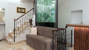 Uma escadaria com piso de mármore, um banco acolchoado e um corrimão decorativo.