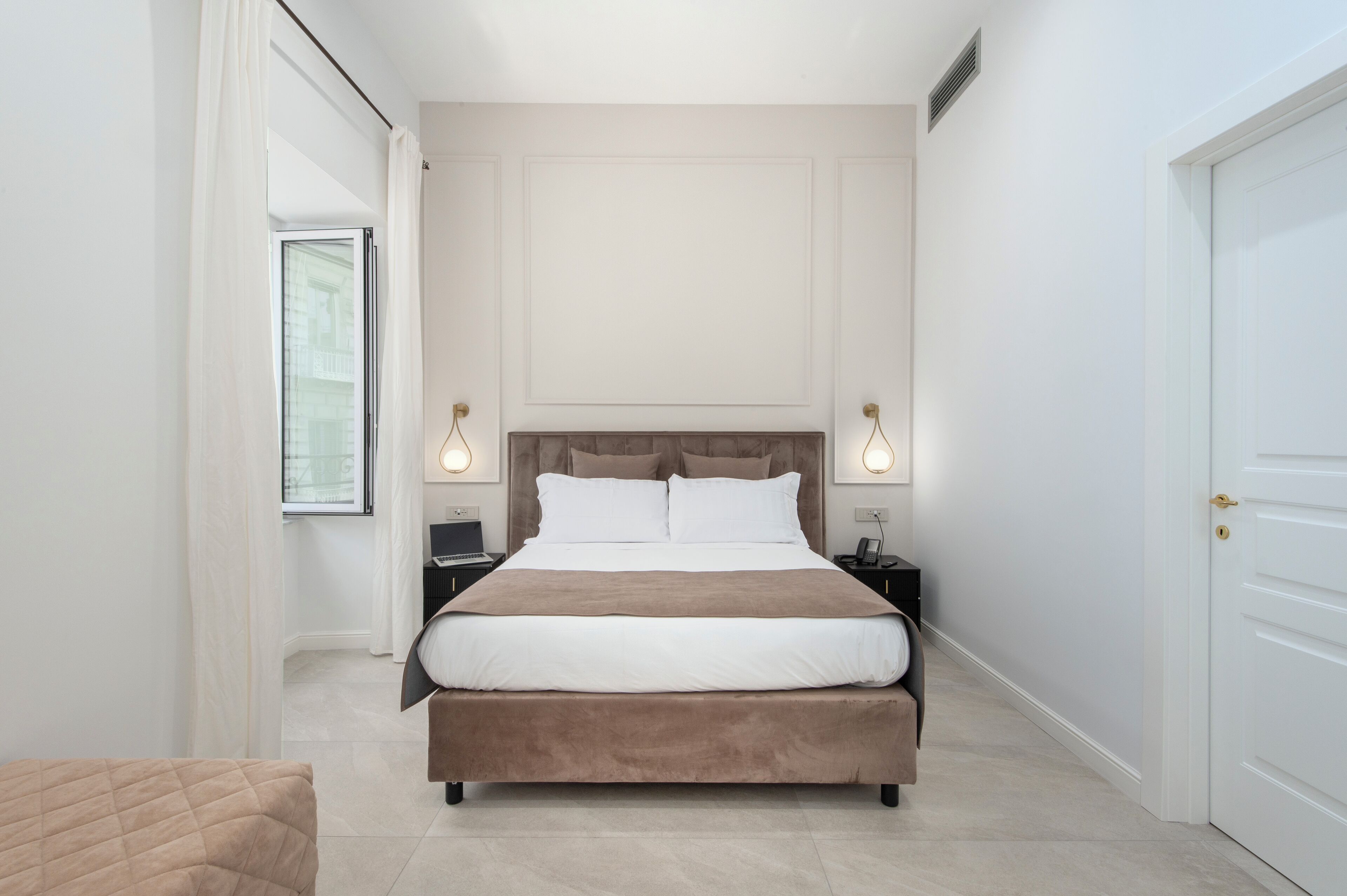 Un dormitorio moderno con una cama grande, lámparas de noche y vistas a través de una ventana.