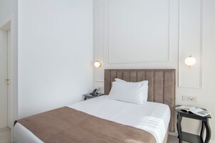 Een hotelkamer met een bed, nachtkastje en een bijzettafeltje met een telefoon.