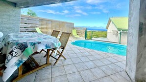 Un espace extérieur abrité comprenant une piscine, une table recouverte d’une nappe et des chaises.