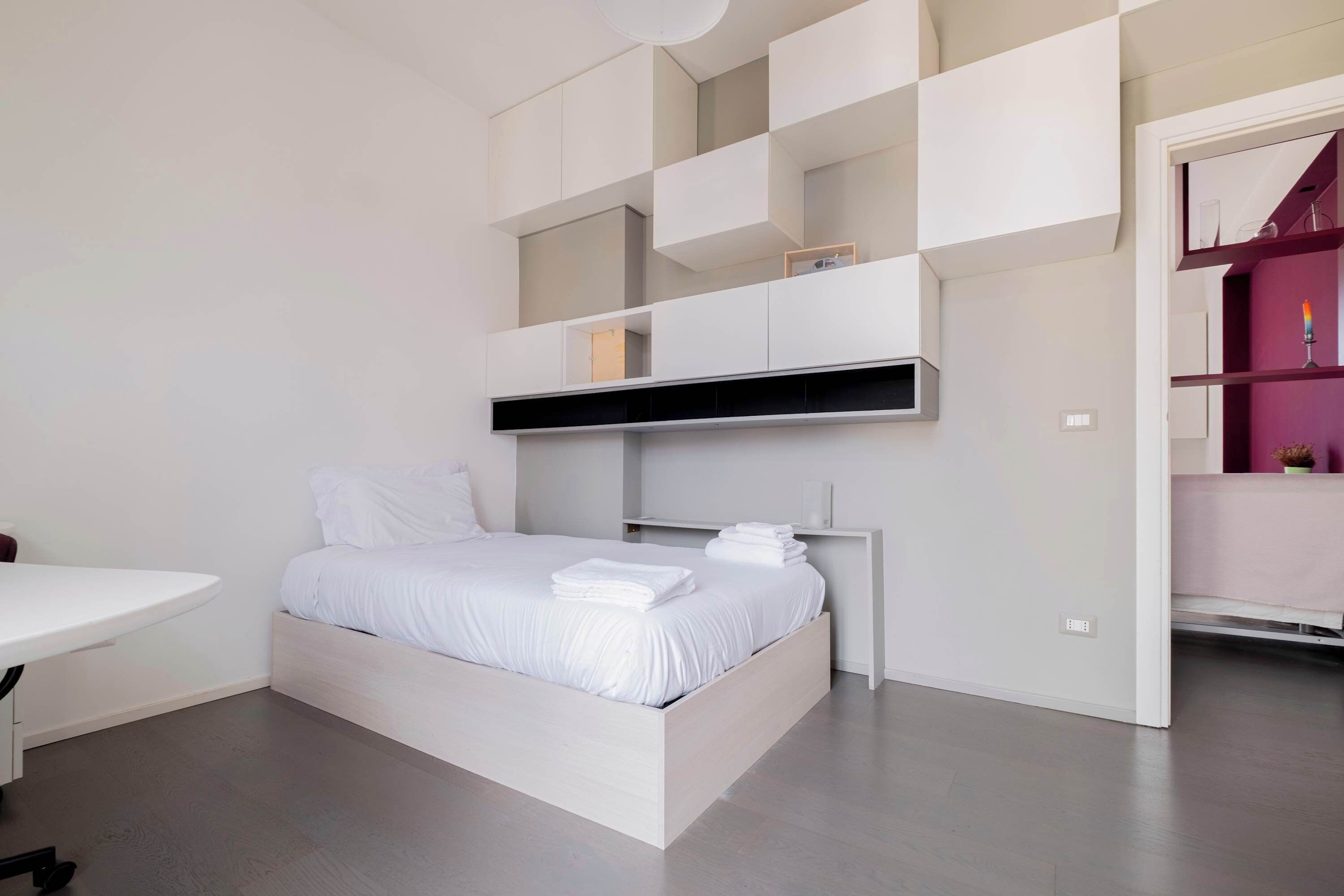 Un dormitorio moderno con cama, escritorio y estanterías empotradas.