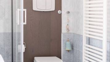 Een moderne badkamer met toilet, douche en een radiator.