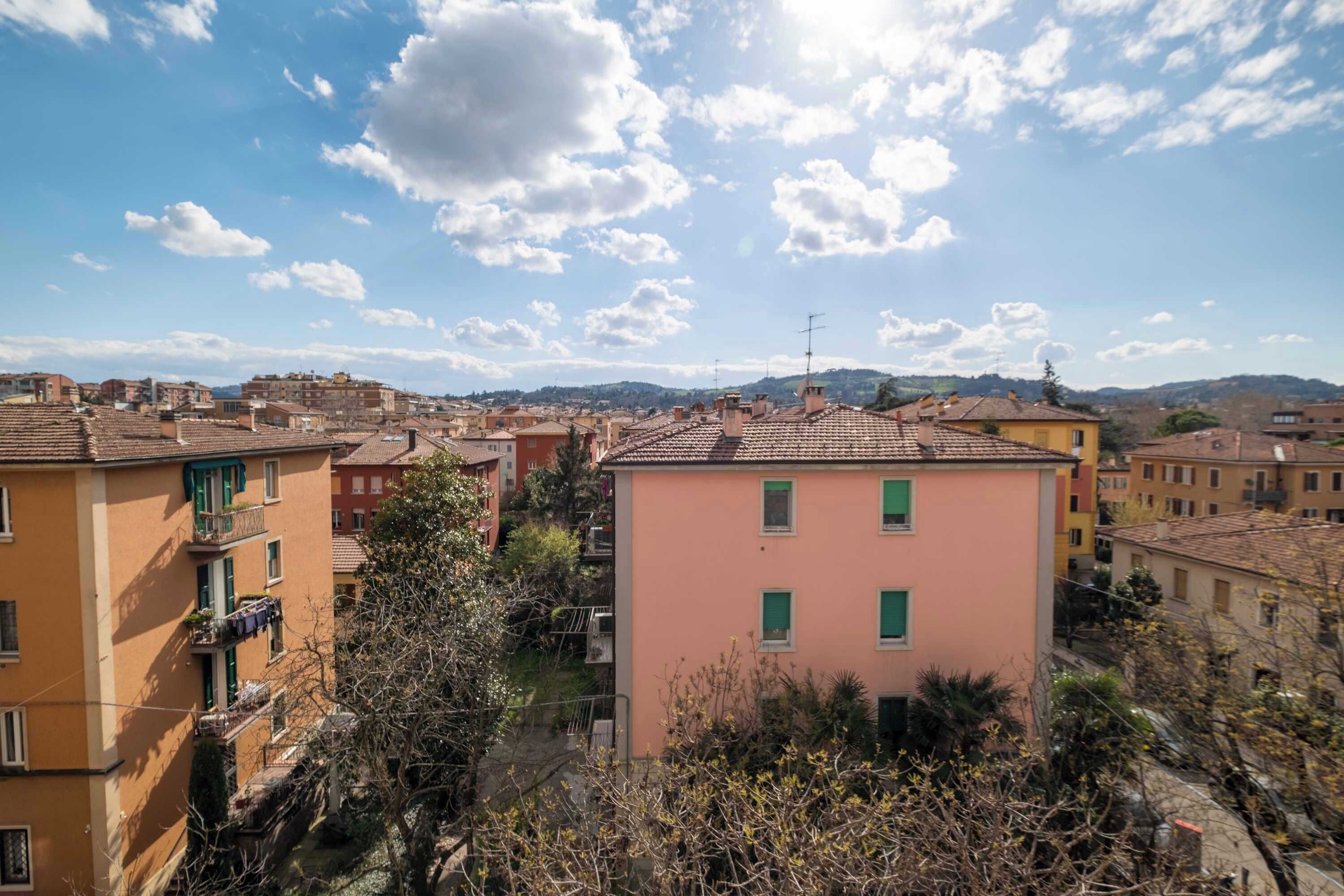 Un quartier résidentiel avec des immeubles à plusieurs étages, dont certains sont dotés de balcons, et un ciel dégagé parsemé de quelques nuages.