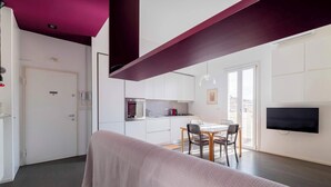 A modern kitchen with white cabinets, a dining area with a table and chairs, and a television mounted on the wall. - Casa Marion Stile e Comfort in un Elegante Dimora Bolognese (Bologna)