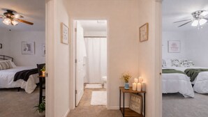 A hallway leading to two bedrooms, each with a bed, a ceiling fan, and a framed picture on the wall. - Copper Ridge RetreatPrivate 2 Bedroom 2Bath Pet Friendly,fenced back yard (Stillwater)