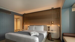Hotelkamer met een groot bed, nachtkastjes, een zithoek en een decoratief wandpaneel.