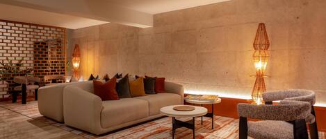 Una sala de estar moderna con sofá, sillones, una mesa de centro e iluminación decorativa.