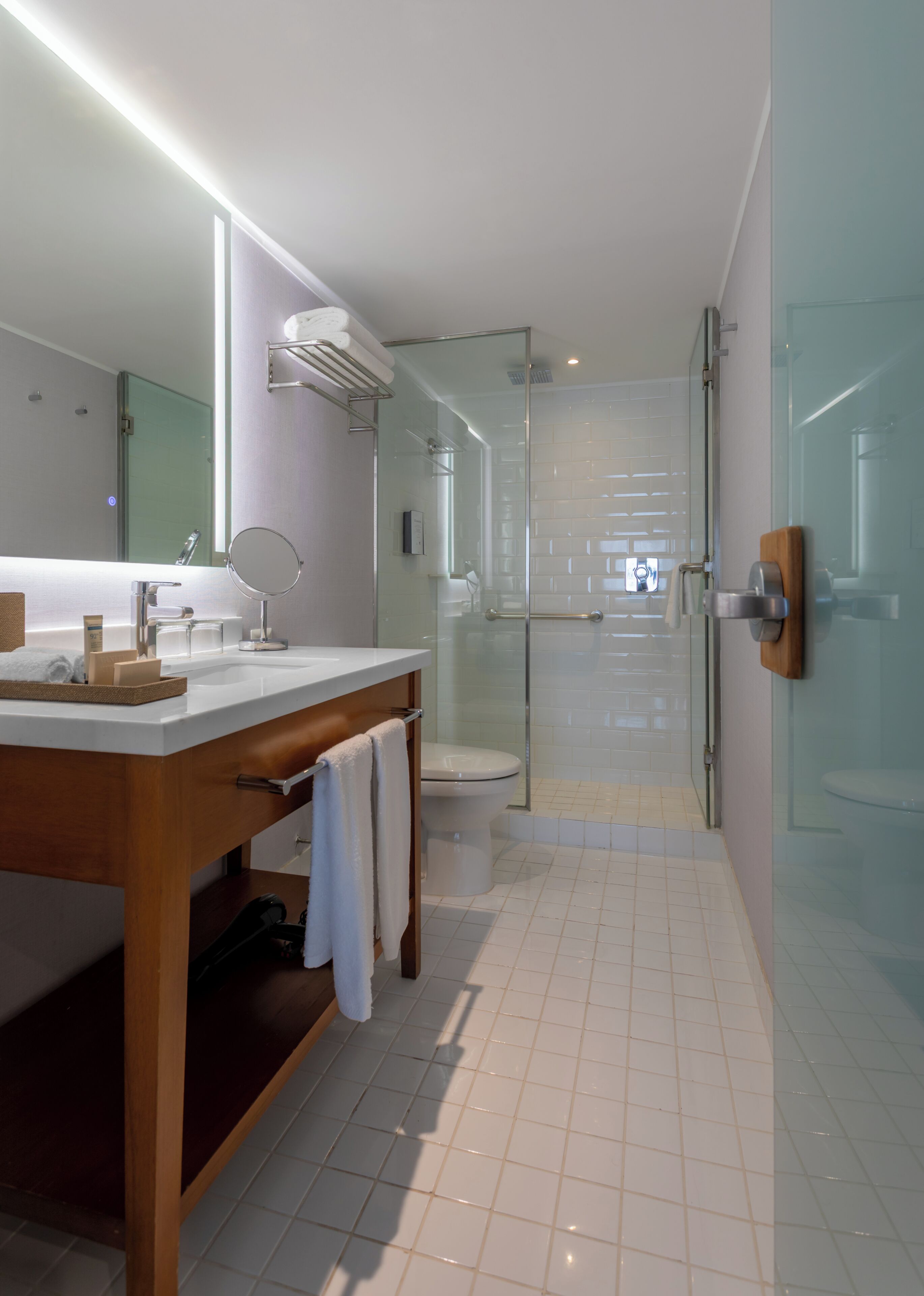 Un baño moderno con cabina de ducha de vidrio, tocador con espejo y un inodoro.