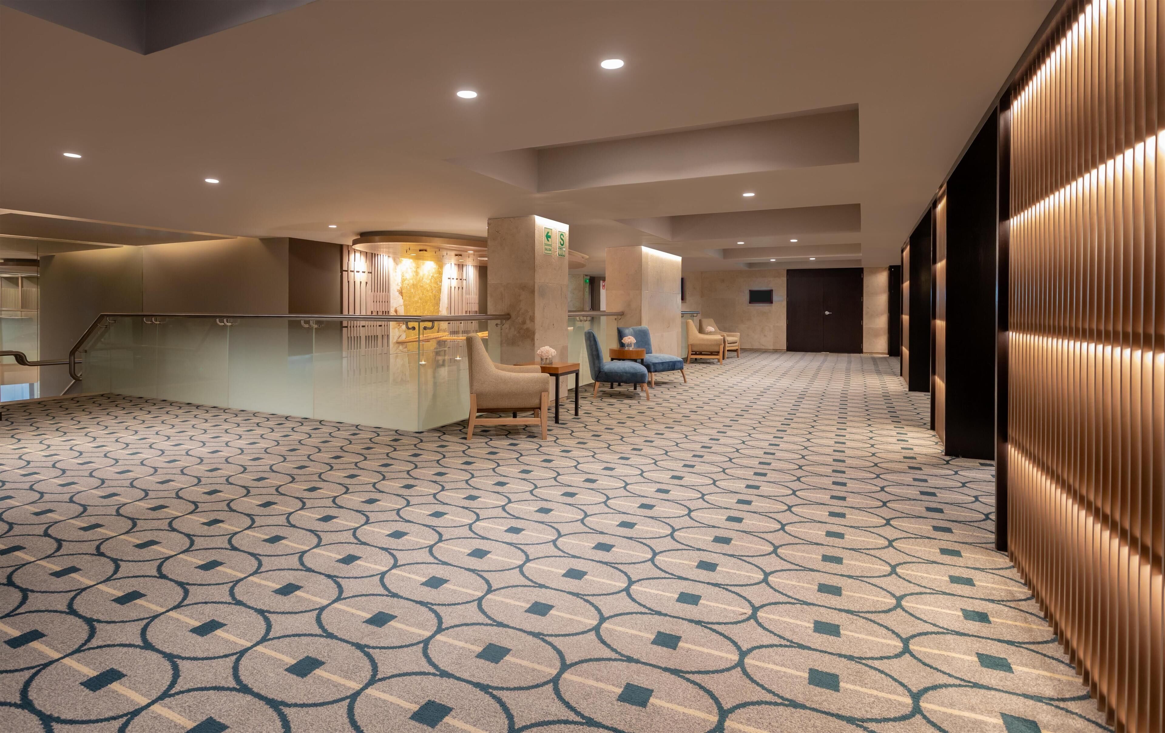 A spacious lobby with a patterned carpet, seating area, and a reception desk.